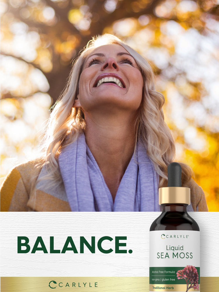 Lifestyle image of smiling woman outdoors with Carlyle Liquid Sea Moss bottle and graphic stating BALANCE.