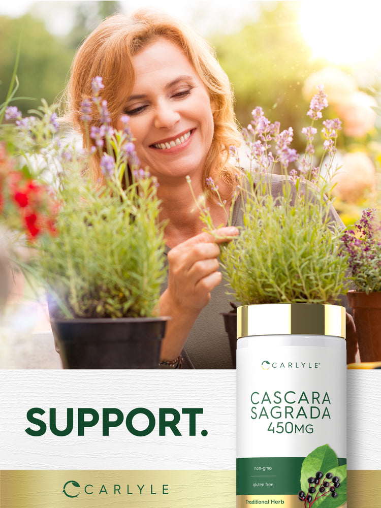 Adult smelling flowering plants in a garden with Piping Rock Cascara Sagrada 450 mg supplement bottle displayed in the foreground