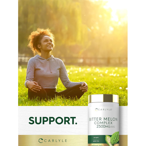 View 6 Young adult woman sits cross-legged in a grassy field, smiling upward with a Carlyle Bitter Melon Complex bottle beside her.