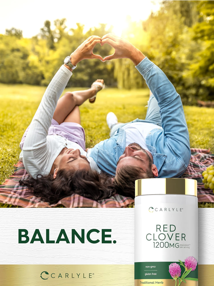 A young couple on a blanket makes a heart with their hands, featuring a Carlyle Red Clover bottle.
