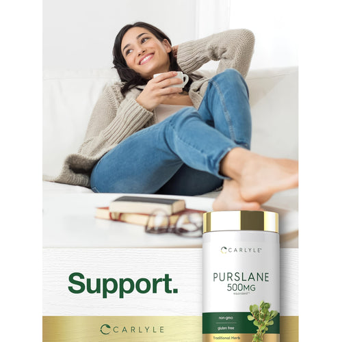 View 6 A young woman relaxes on a couch, holding a cup near a Carlyle Purslane 500 mg bottle, creating a serene lifestyle scene.