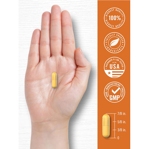 View 7 A hand holds a single yellow Turmeric 500 mg with Bioperine capsule, measuring 7/8 inch long.