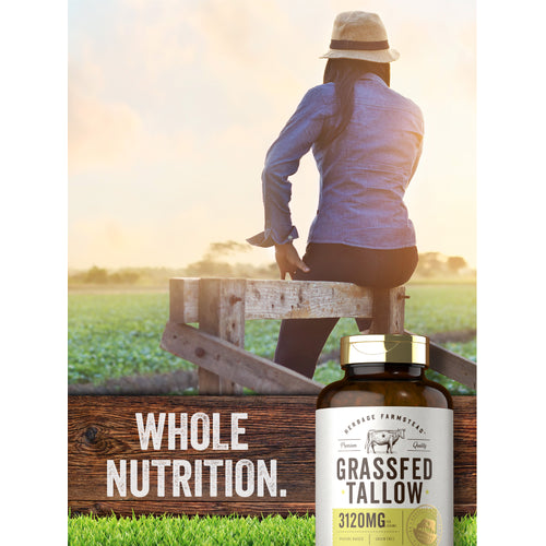 View 13 Lifestyle image of adult sitting on a wooden fence overlooking a field with Heritage Farmstead Grassfed Tallow 3120MG supplement bottle nearby