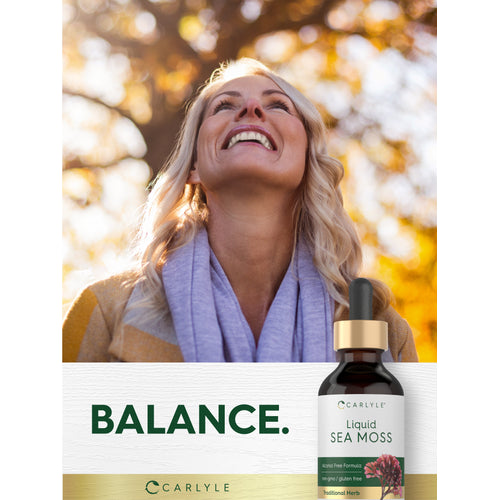 View 10 Lifestyle image of smiling woman outdoors with Carlyle Liquid Sea Moss bottle and graphic stating BALANCE.