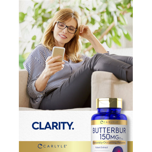 View 12 Middle-aged woman smiling at her phone on a couch, next to a Butterbur bottle.