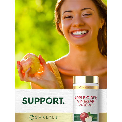 View 6 A young woman smiles while holding an apple beside a bottle of Carlyle Apple Cider Vinegar.