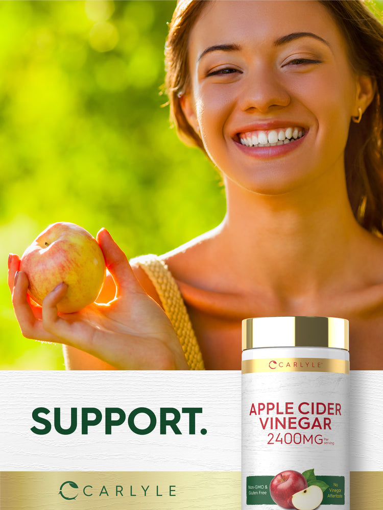 A young woman smiles while holding an apple beside a bottle of Carlyle Apple Cider Vinegar.