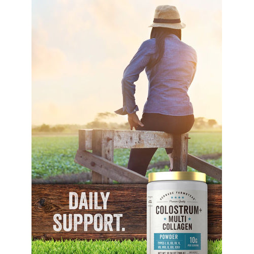 View 6 A woman in a straw hat and denim shirt sits on a wooden fence, looking at a sunny field, with a tub of Colostrum & Collagen Powder.